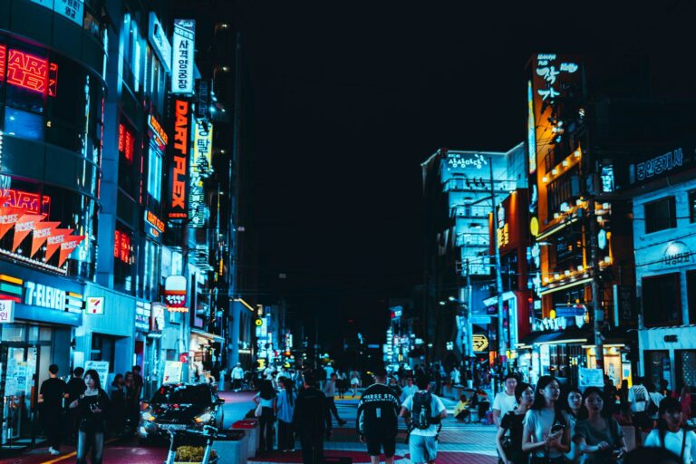 Beleuchtete Neonschilder und Geschäfte in einer Straße in Hongdae, Seoul, bei Nacht